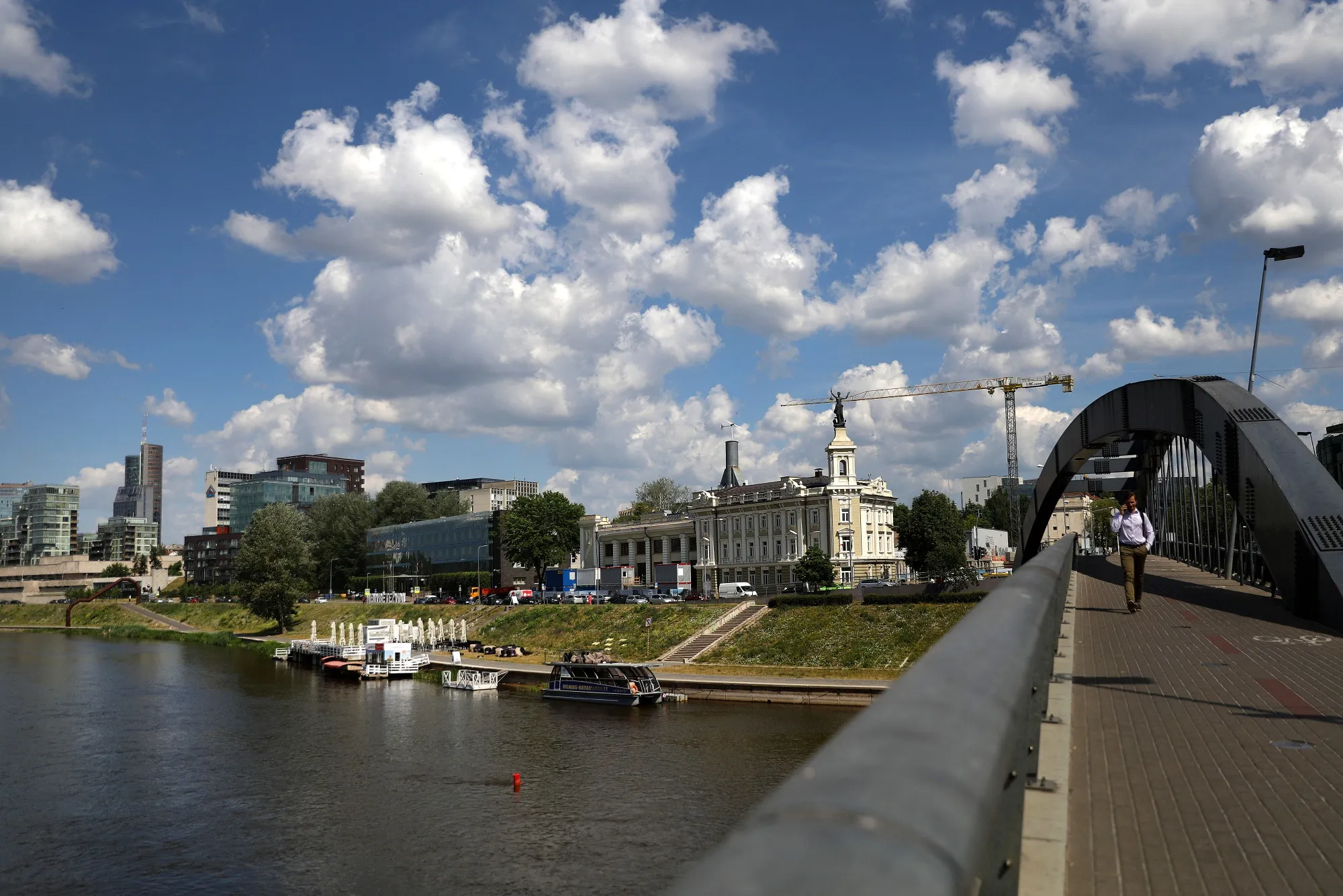 A pedestrian crosses a footbridge spanning the river Neris in Vilnius, Lithuania.