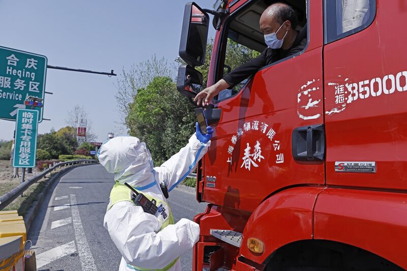 Водитель представляет свой отрицательный сертификат теста на нуклеиновую кислоту сотруднику дорожной полиции в Шанхае 11 апреля.