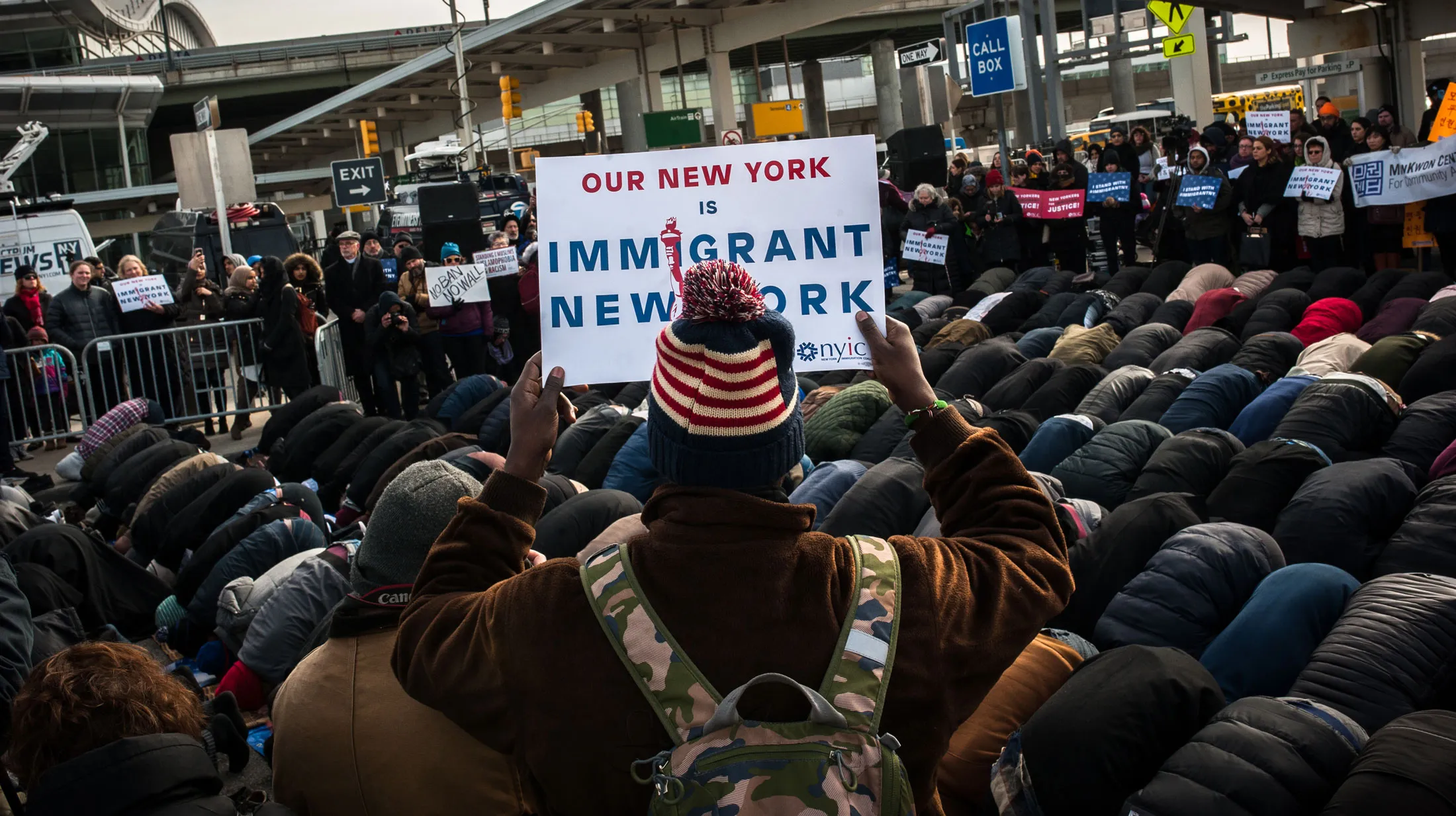 A group of Muslim men pray while supporters hold up signs during an interfaith prayer and rally at John F. Kennedy Airport (JFK) to protest U.S. President Donald Trump's travel ban on immigrants and refugees.
