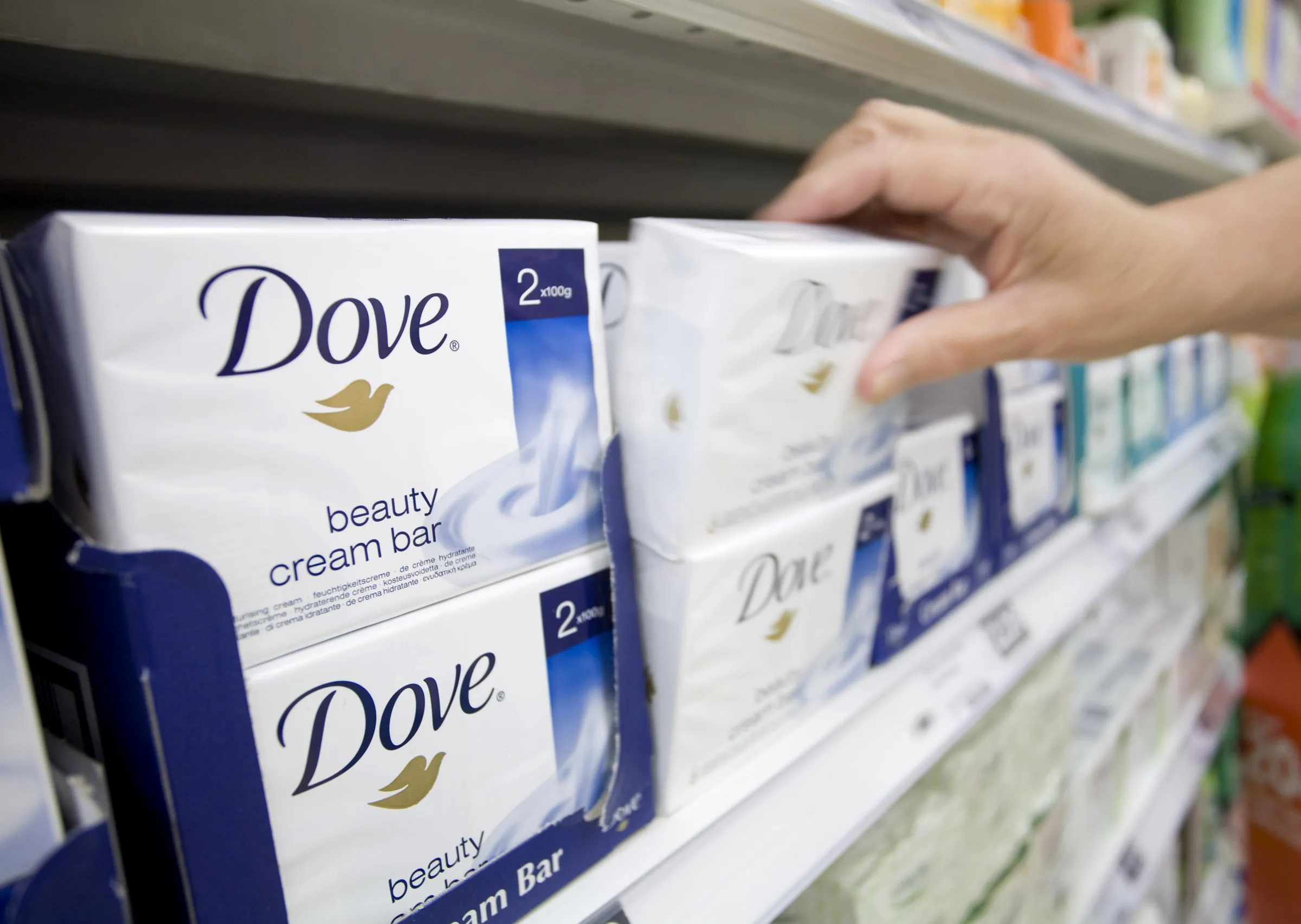 A customer selects a packet of Dove soap, produced by Unilever Plc., at a supermarket in London.