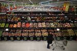 A customer pushes a shopping cart as she browses for produce in the fruit and vegetable section of an Asda supermarket, operated by Wal-Mart Stores Inc., in the Wembley district of London.