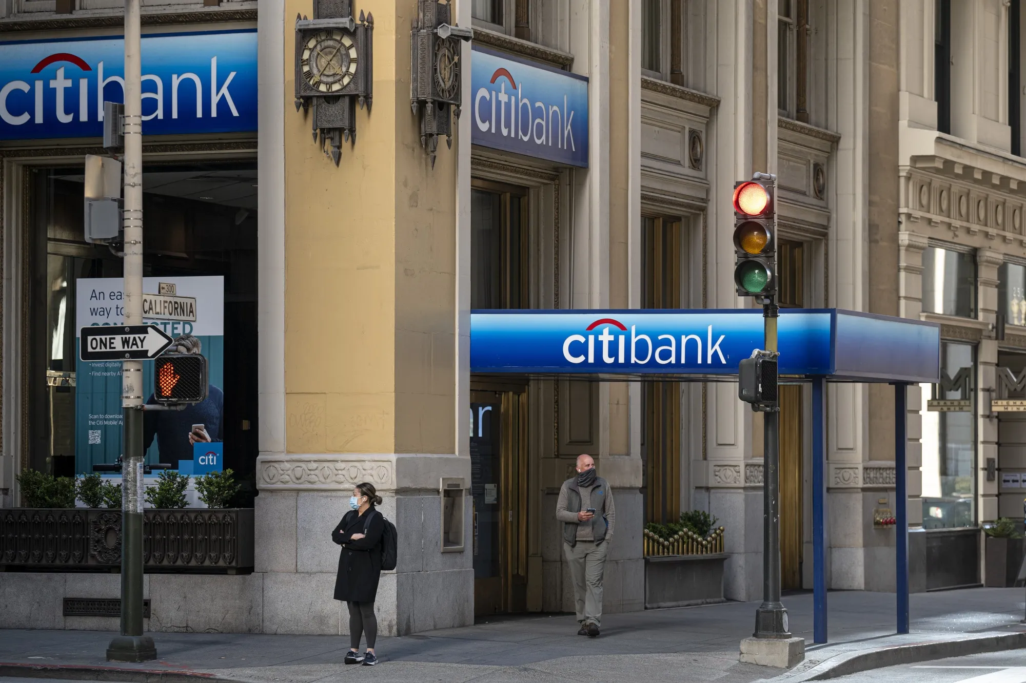 A pedestrian wearing a protective mask walks past a Citibank bank branch in San Francisco, California, U.S.