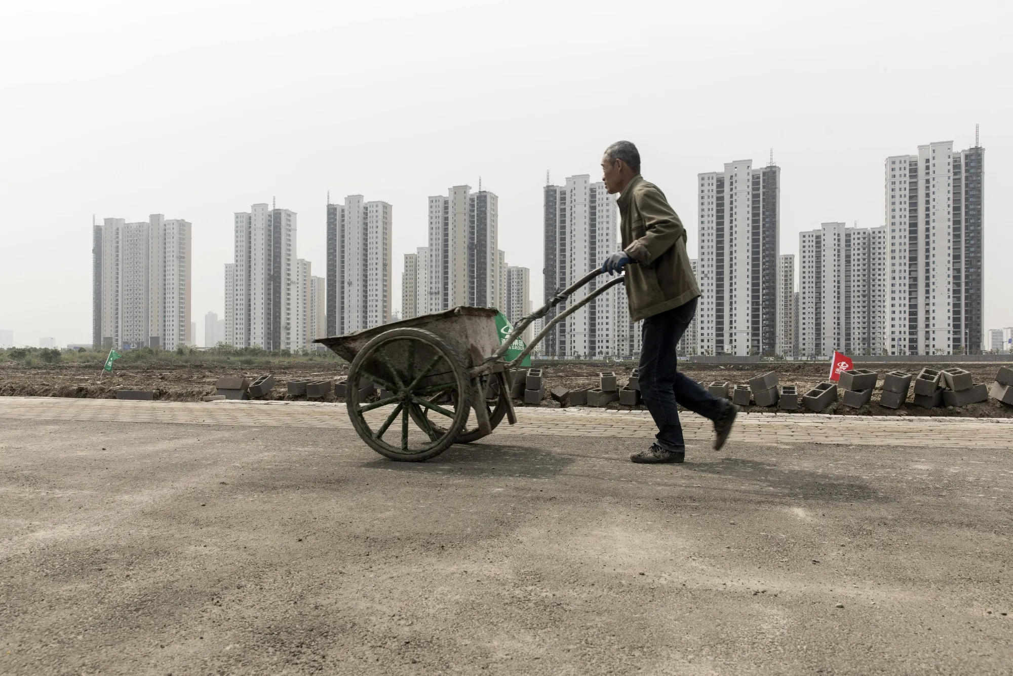 A worker pushes a wheel barrow past a construction site for a secondary school at Hangzhou Bay New Zone in Ningbo, China, on&nbsp;April 26.