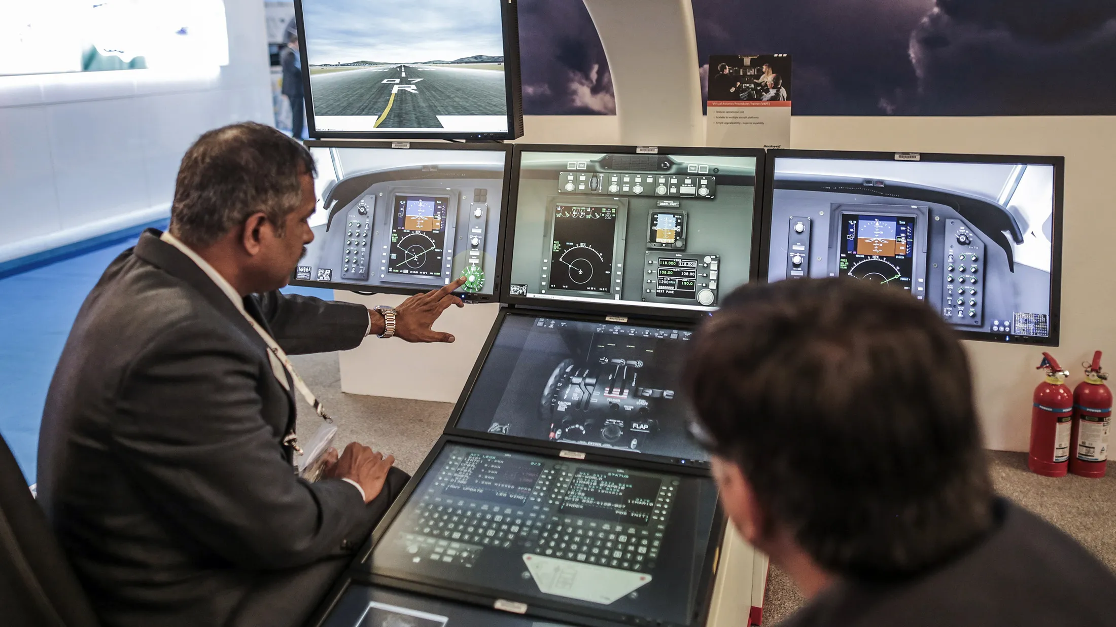 An employee, left, shows simulation system to an attendee at the Rockwell Collins Inc. booth during the Aero India air show at Air Force Station Yelahanka in Bengaluru, India, on Thursday, Feb. 19, 2015. The bi-annual Aero India exhibit is the premier event for nations and companies to get a piece of the $150 billion that the world's biggest arms importer plans to spend on modernizing its military.
