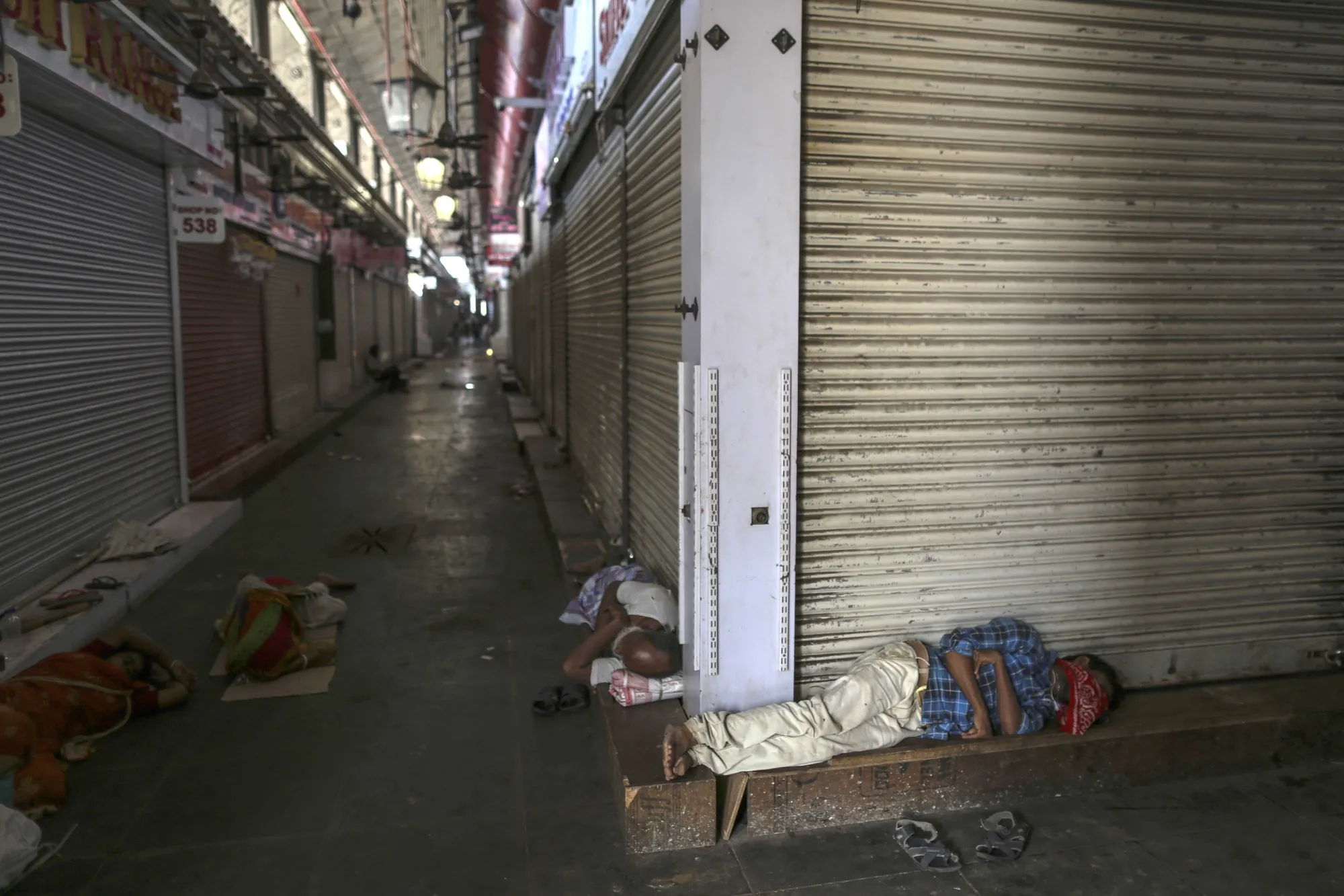 People sleep outside shuttered stores at Crawford Market during a lockdown in Mumbai, March 25.