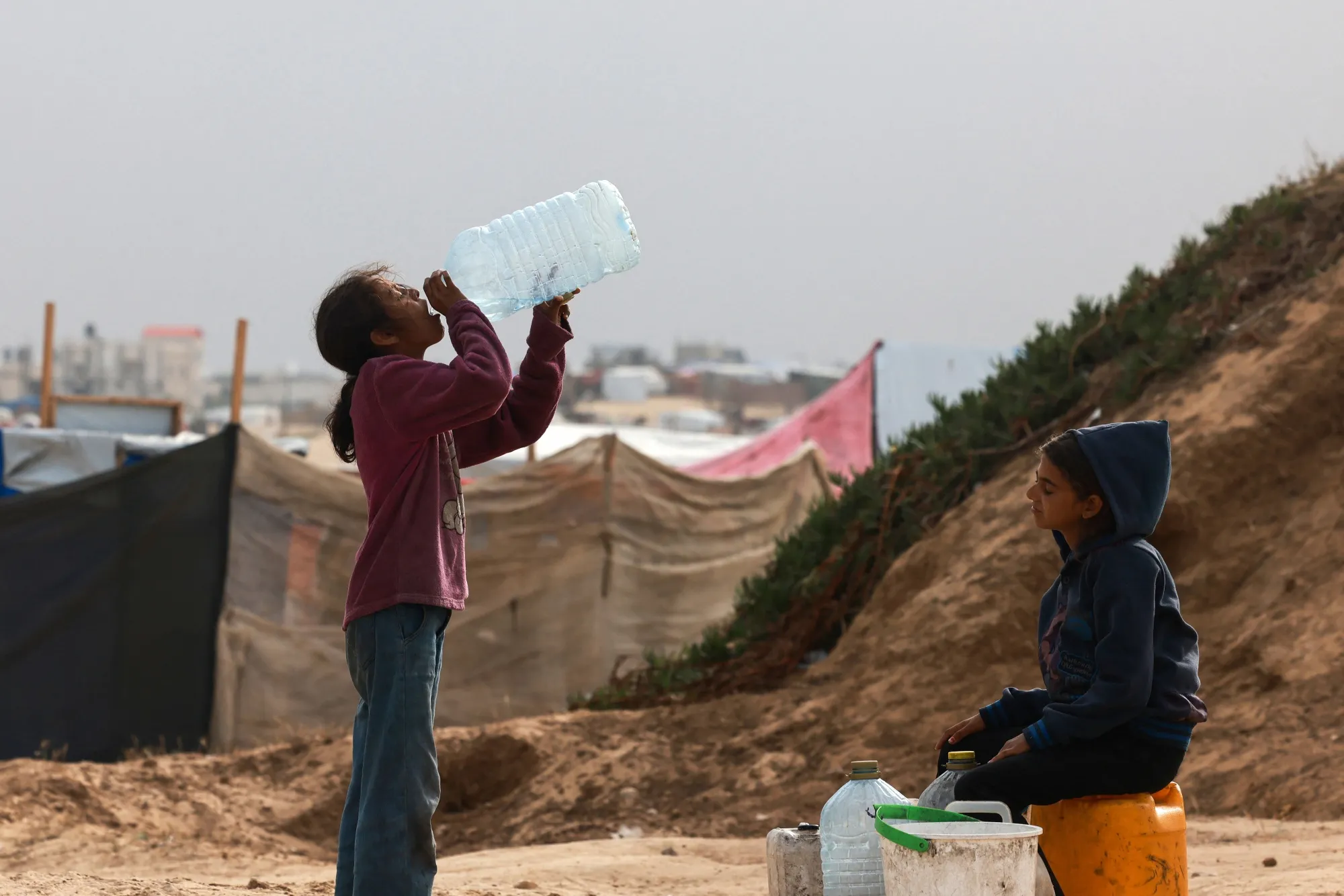 Displaced Palestinian children wait for a water supply tank amid soaring temperatures in Rafah.