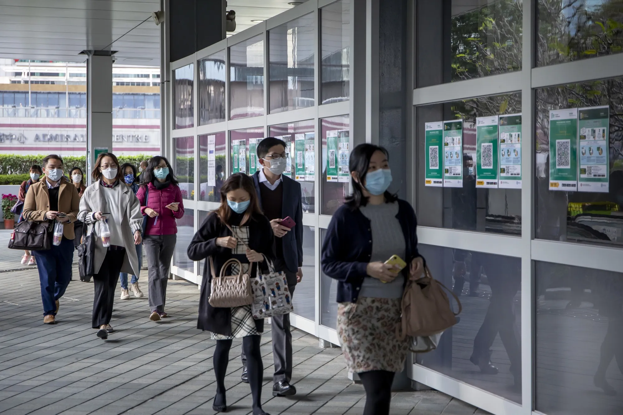 People walk past QR codes for the LeaveHomeSafe Covid-19 contact-tracing app, in Hong Kong.