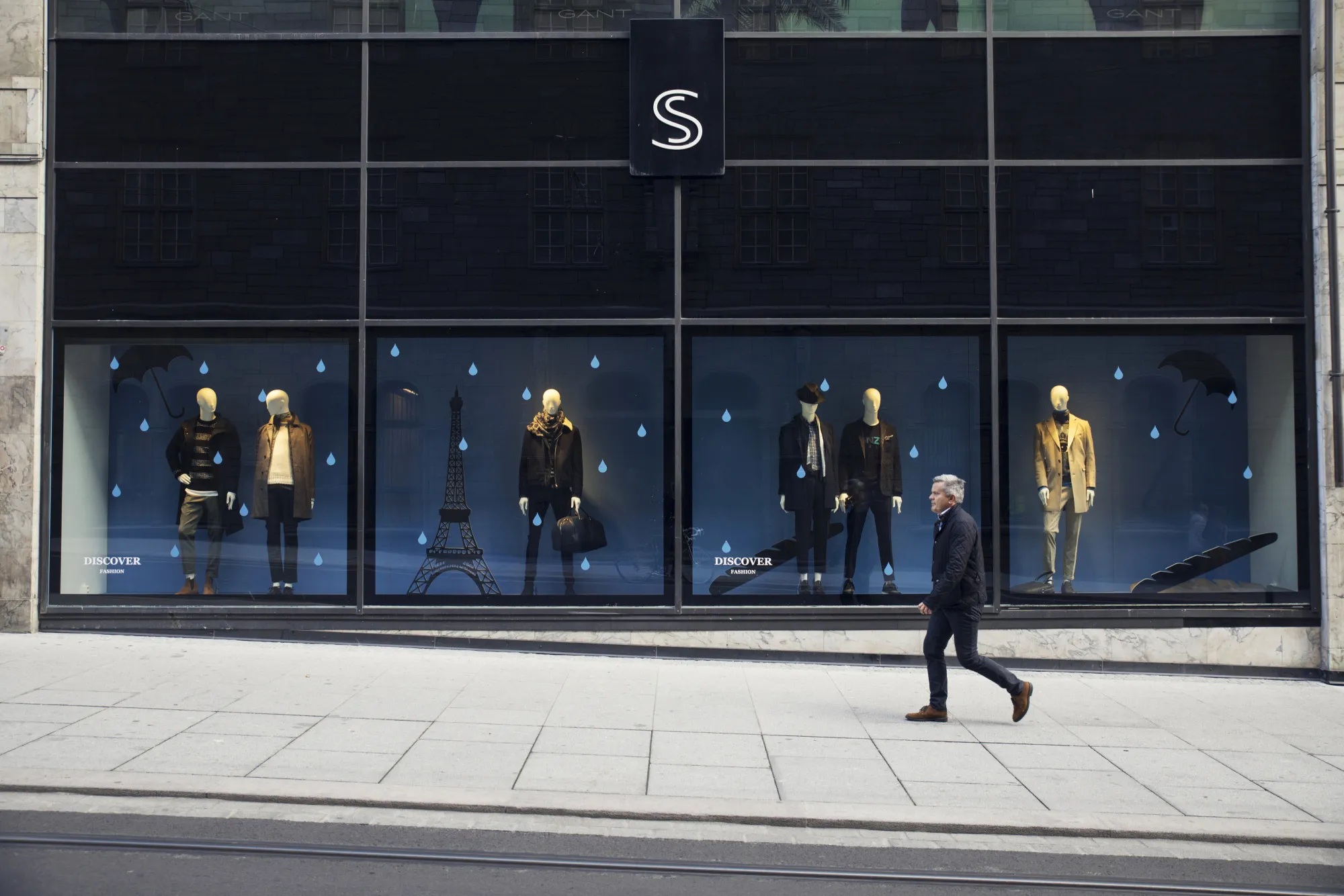 A pedestrian passes a store window in Oslo.