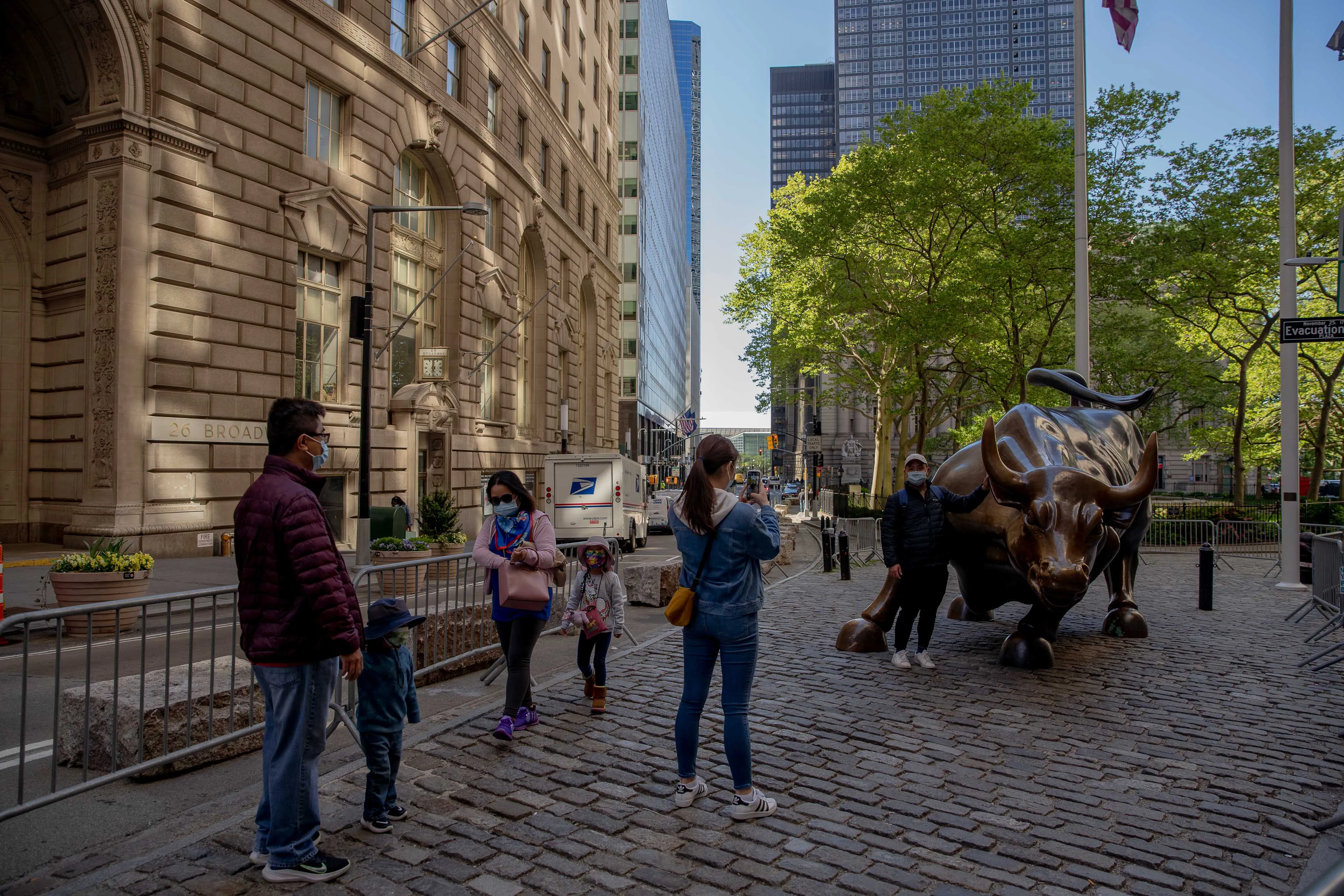 People take photographs in front of the Charging Bull bronze statue in the Financial District of New York.