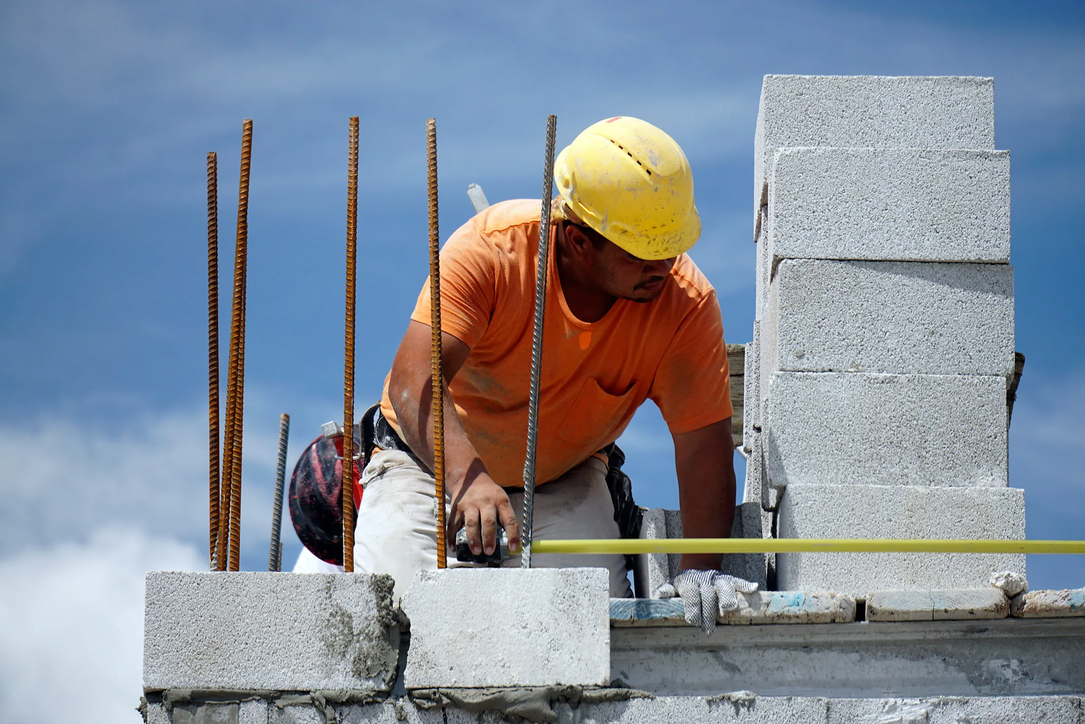 A construction worker uses a measuring tape while building a wall of a home in Doral, Fla., on Aug. 12.
