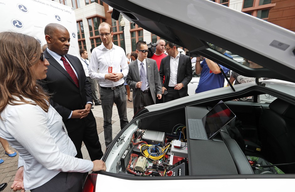 U.S. Department of Transportation Secretary Anthony Foxx, second from left, looks at some of the computers in a self-driving car after a news conference.