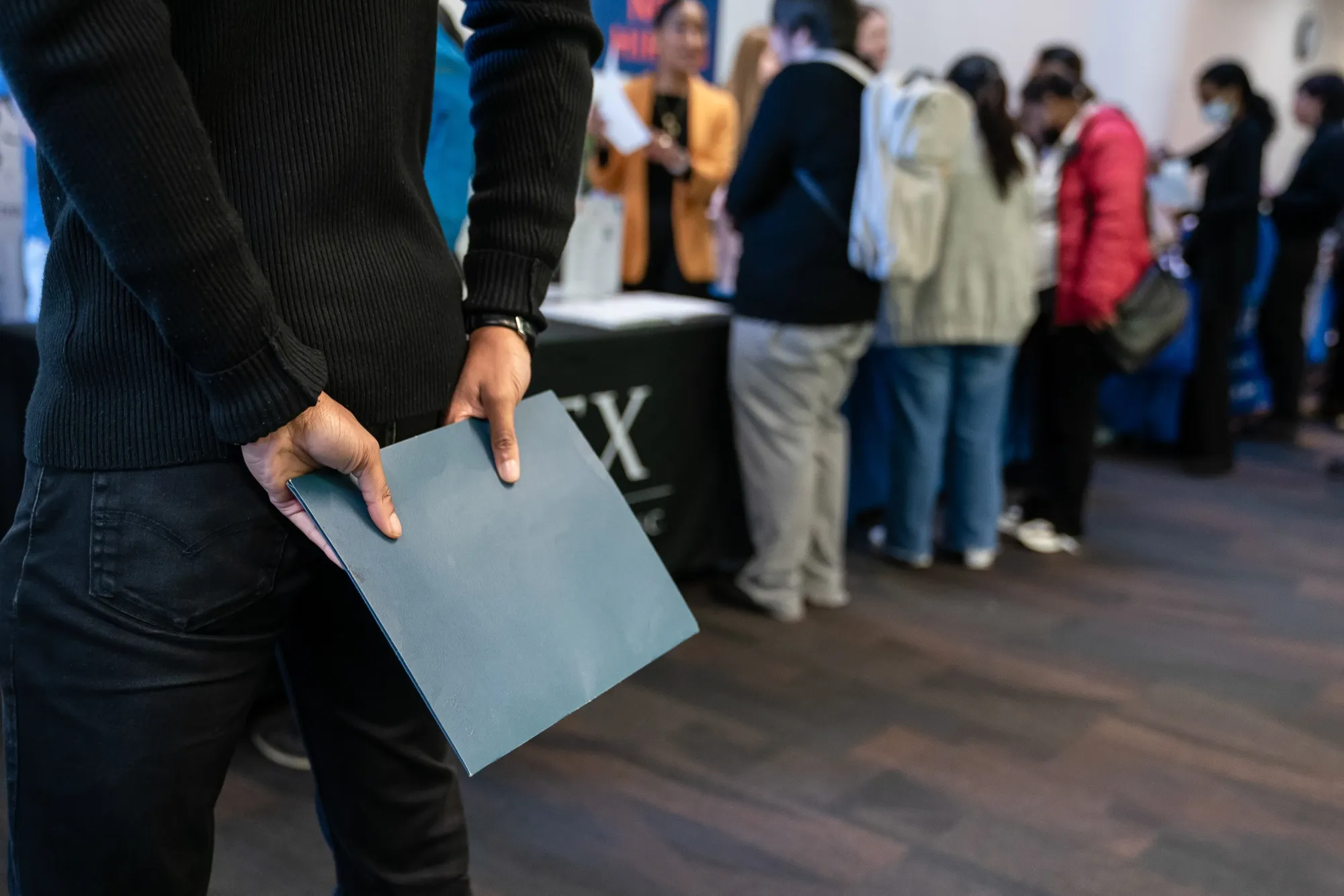 A jobseeker holds a folder while waiting to speak with a recruiter during a career fair in Seattle.