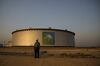 An employee visits the site of crude oil storage tanks at the Juaymah tank farm at Saudi Aramco's Ras Tanura oil refinery and oil terminal in Ras Tanura, Saudi Arabia, on Monday, Oct. 1, 2018. Saudi Aramco aims to become a global refiner and chemical maker, seeking to profit from parts of the oil industry where demand is growing the fastest while also underpinning the kingdom’s economic diversification.