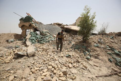 A member of the Iraqi government forces walks amid the rubble of a destroyed building on the front line near the village of al-Azraqiyah, northwest of the city of Fallujah, on June 5, 2016.