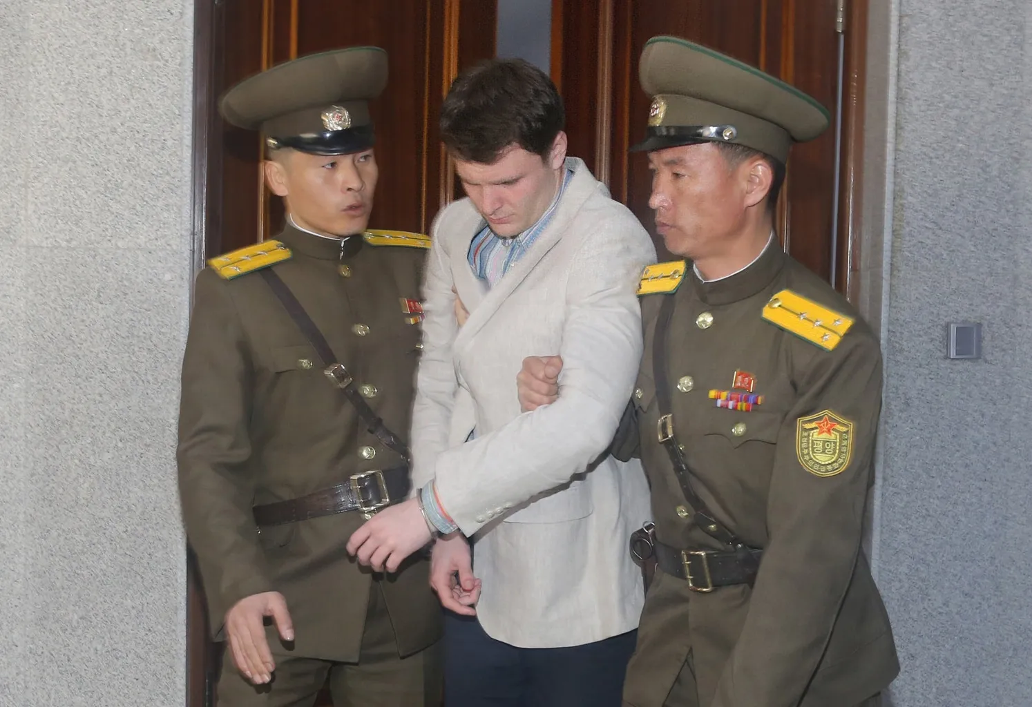 American student Otto Frederick Warmbier, center, is escorted out of the courtroom after his trial in Pyongyang, capital of the Democratic People's Republic of Korea, on March 16, 2015.
