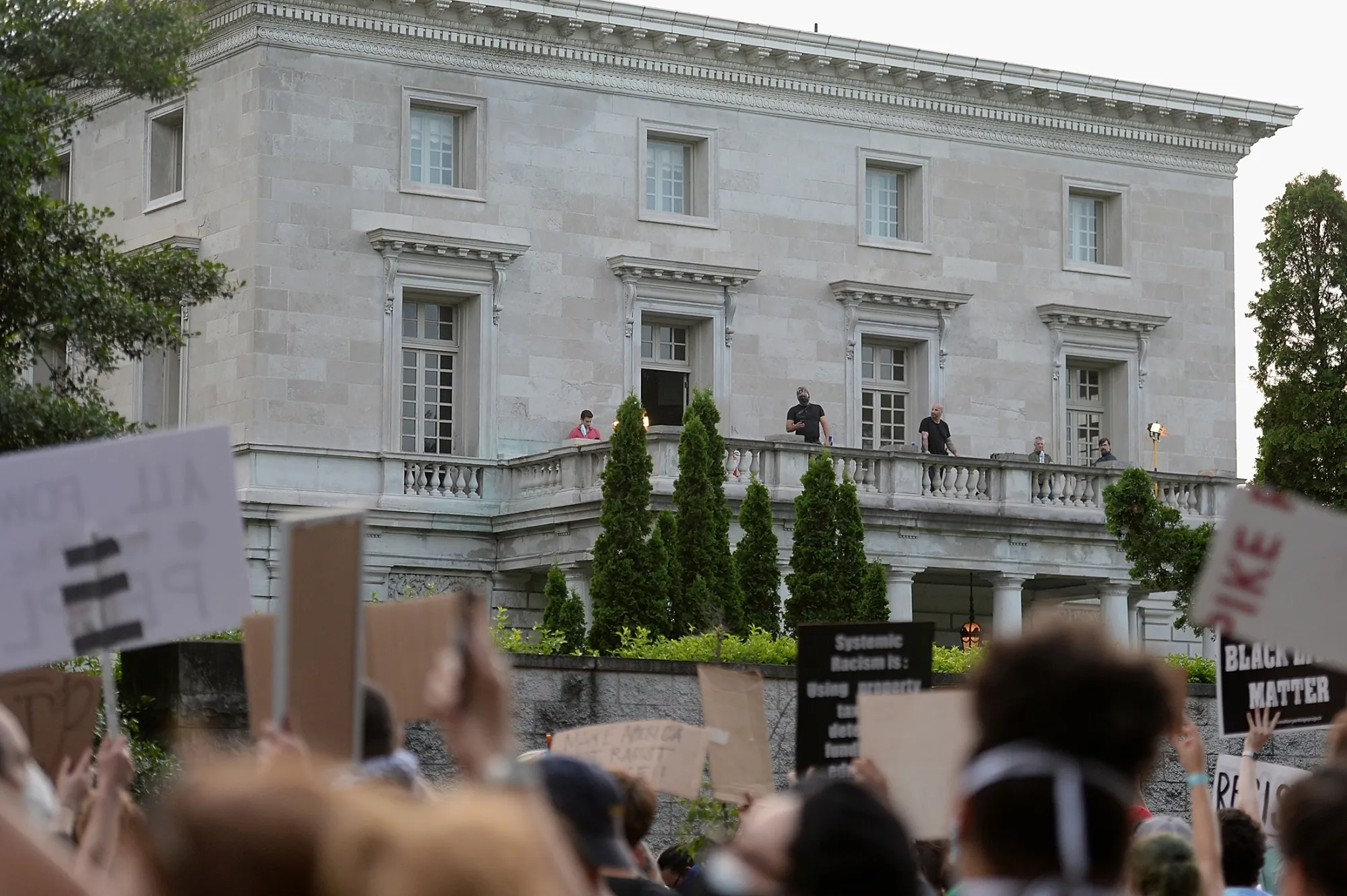 Security personnel stand on the balcony at the home of Mark and Patricia McCloskey as protesters demonstrate outside on July 3.