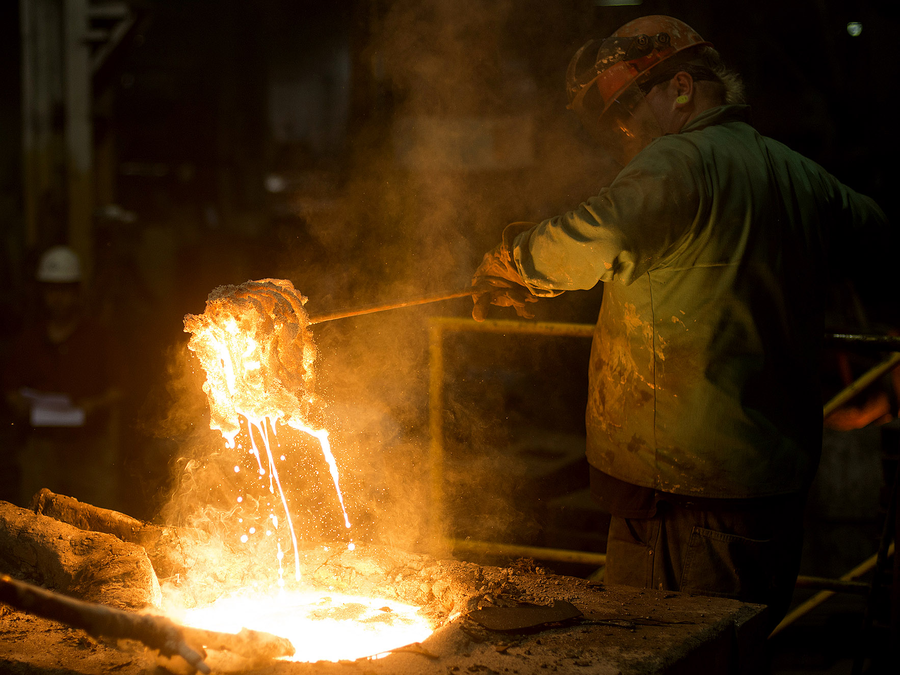 A worker removes slag, a stony waste substance created from the smelting process, from molten metal in a ladle at a facility in Salem, Ohio.