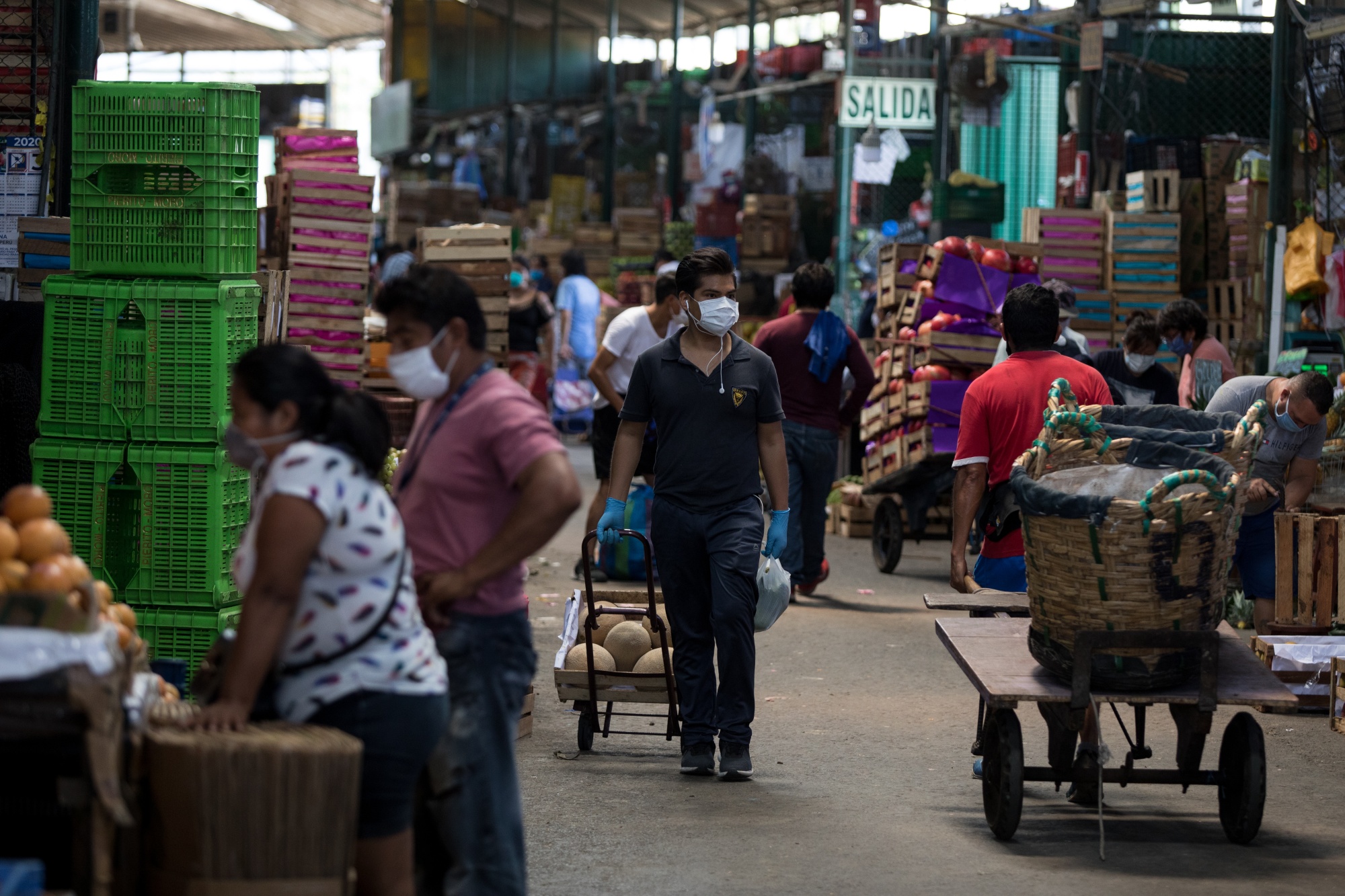 People wearing protective masks shop at a market in Lima, Peru.