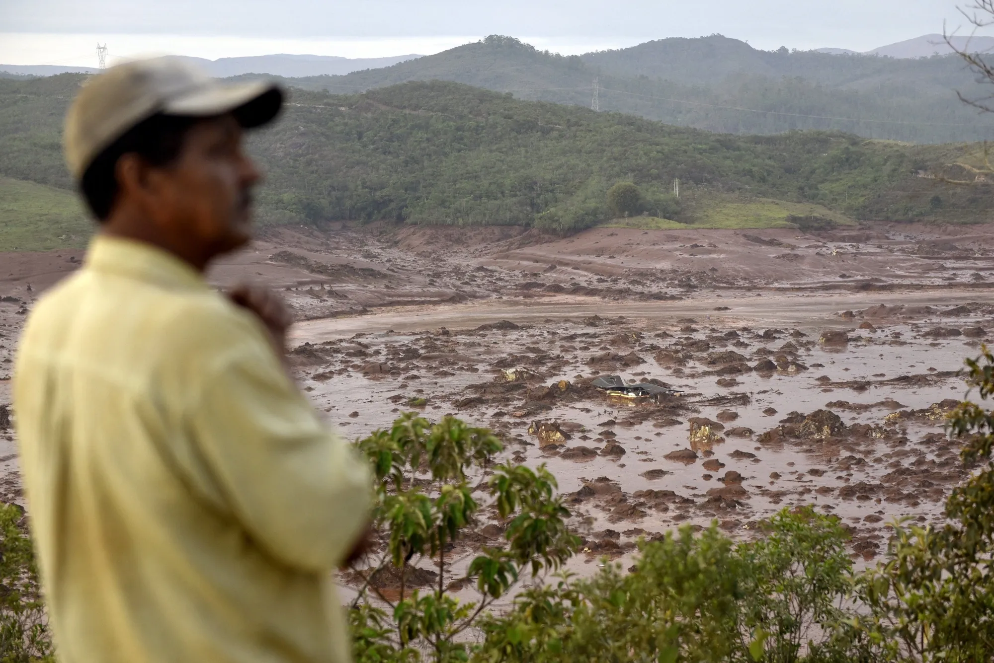A man looks at where a dam burst in the village of Bento Rodrigues, Brazil, in 2015.&nbsp;