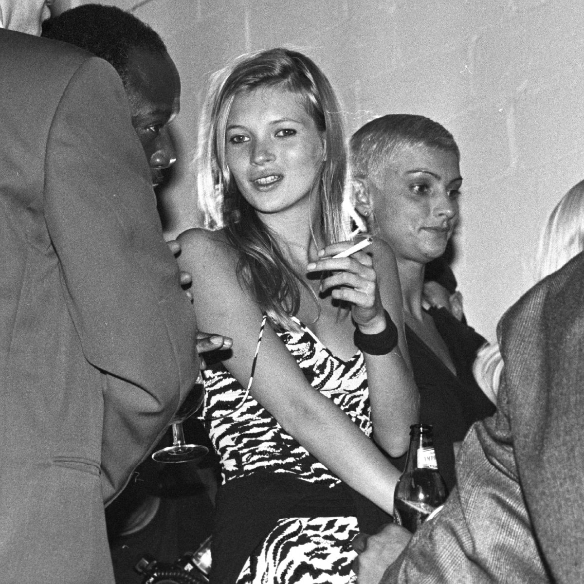 Kate Moss smoking a cigarette at the Versus NYFW after-party in 1995 in grayscale.