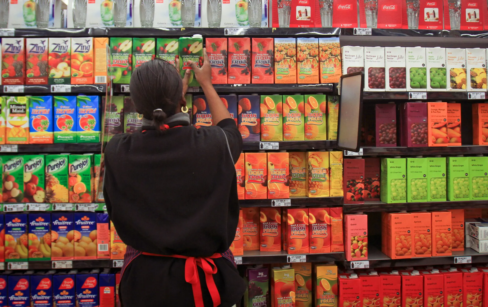 An employee re-stocks shelves with cartons of fruit juice at a Pick n Pay Stores Ltd. supermarket in Johannesburg, South Africa, on Monday, July 25, 2011. Pick n Pay Stores Ltd., South Africa's second-biggest grocer, this month said it plans to fire 3,137 workers, or 8.6 percent of its workforce, to trim labor costs.
