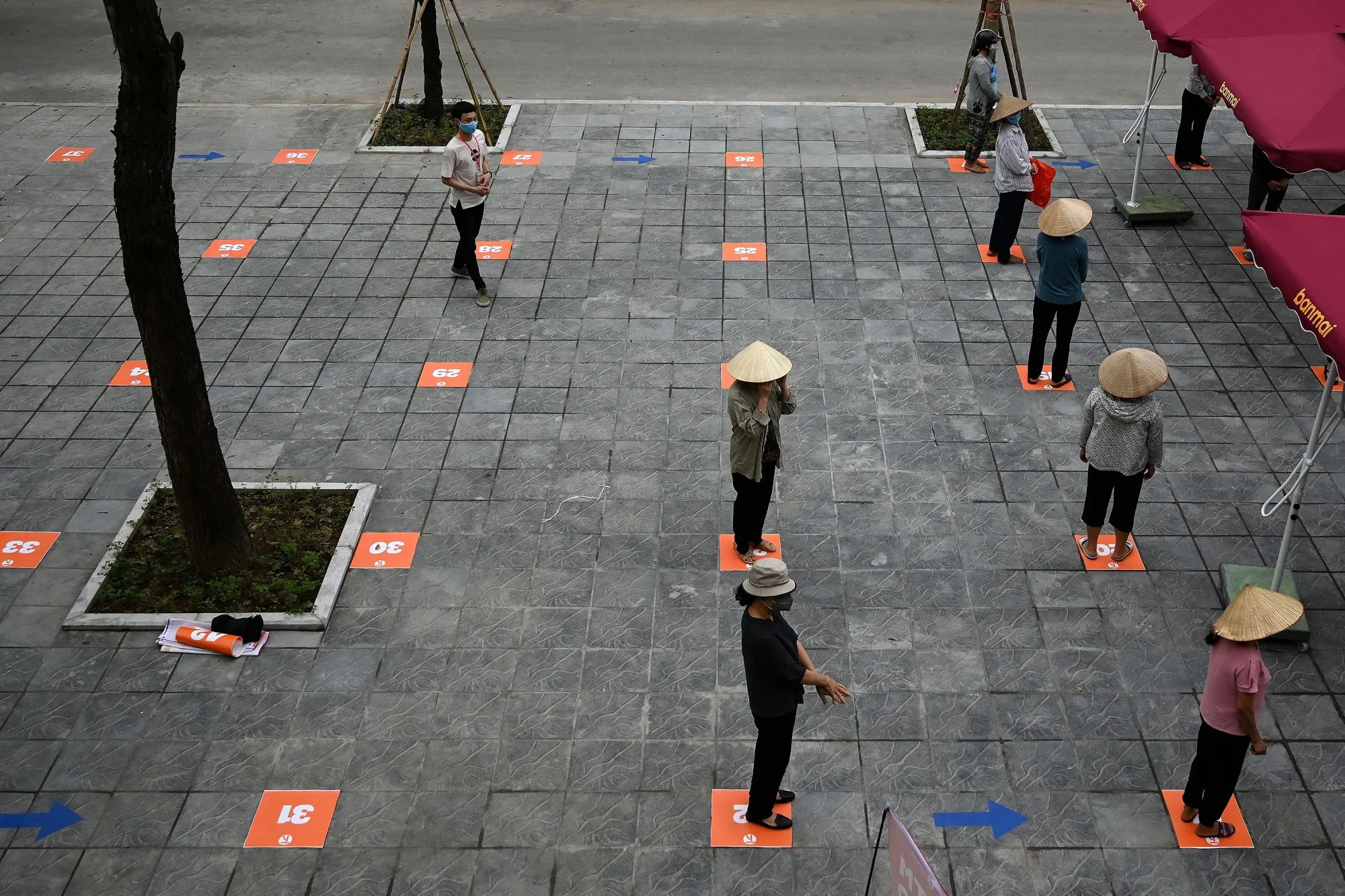 Residents wearing face masks practice social distancing as they wait in a queue for free rice in Hanoi on April 11.