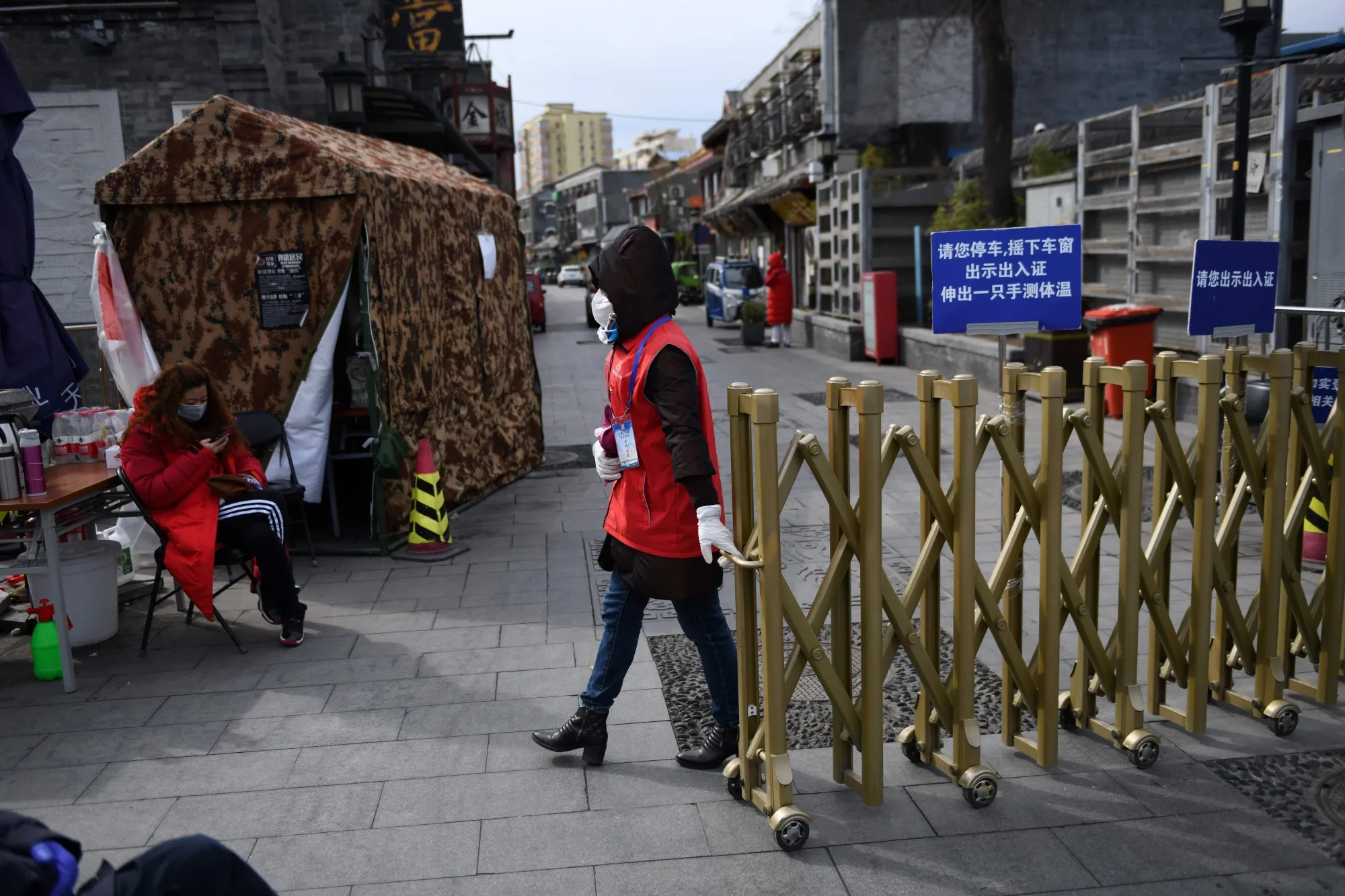 A volunteer closes the gate of an entrance to a residential community in Beijing as they monitor people entering and leaving, on March 26.
