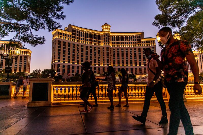 Pedestrians pass in front of the Bellagio Hotel and Casino at night in Las Vegas, Nevada, U.S.