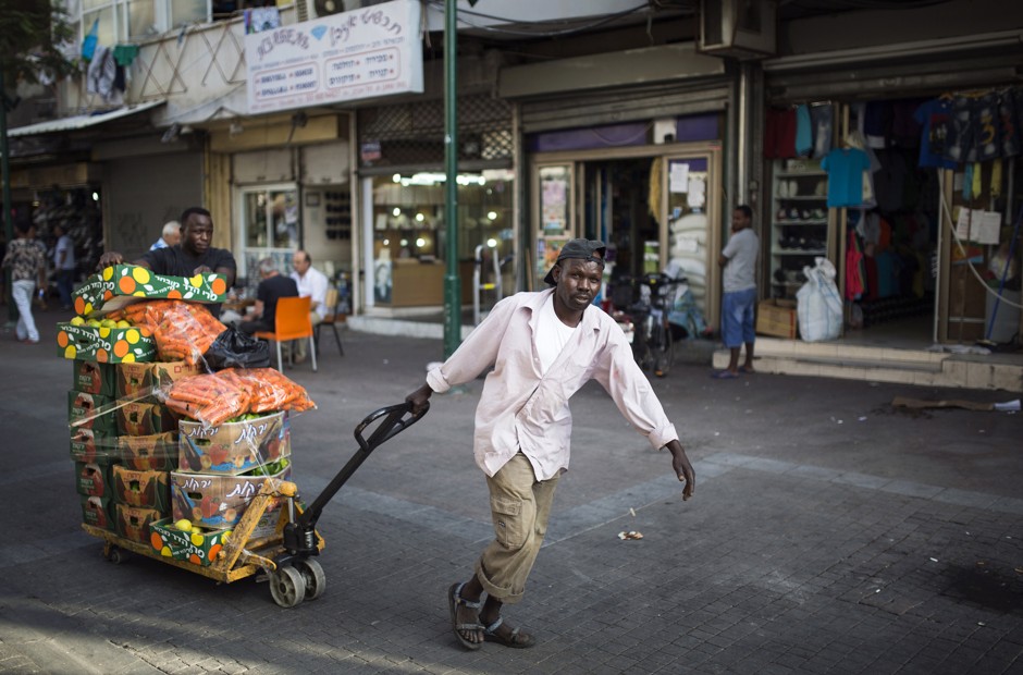 An African immigrant pulls a trolley of vegetables in Tel Aviv.