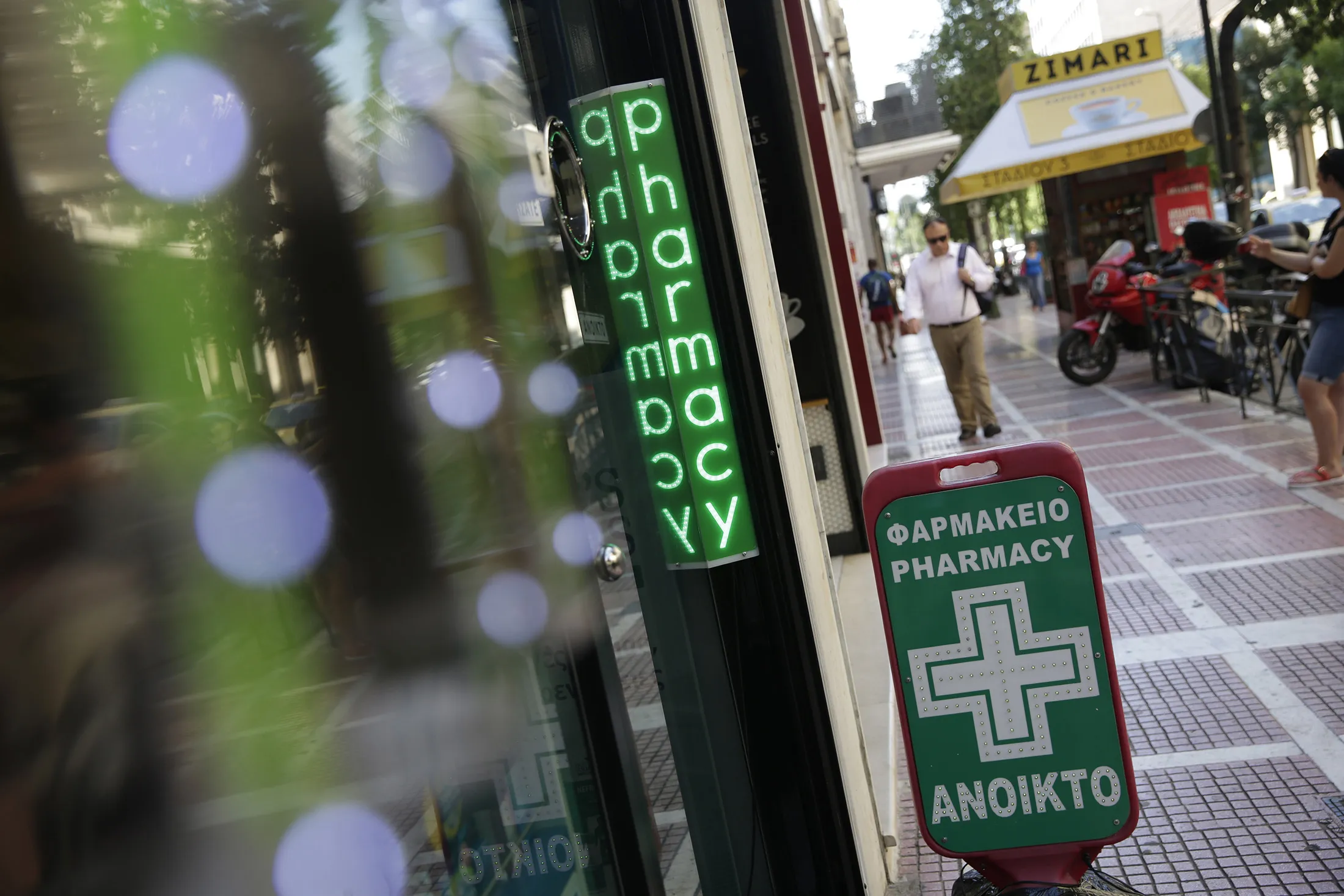 A neon sign sits on display at the entrance to a pharmacy drugstore in Athens, Greece, on Thursday, July 16, 2015. While Greek lawmakers have now passed reform measures demanded by creditors in return for negotiating a third bailout package, that may not yet be enough for the ECB to change its stance.
