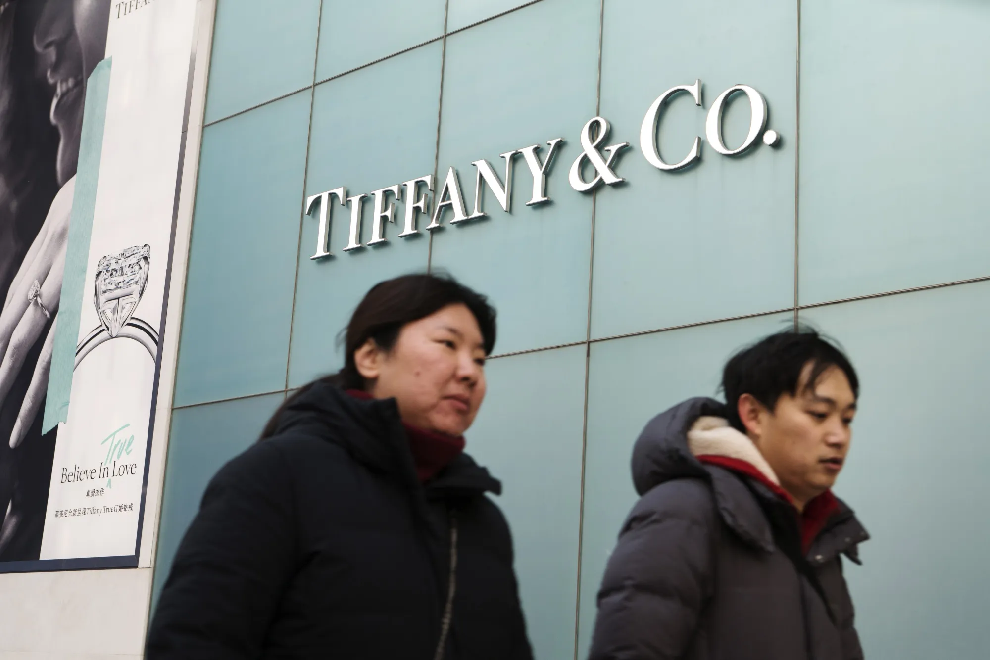Pedestrians walk past a Tiffany &amp; Co. jewelry store in the Wangfujing shopping area of Beijing, China.