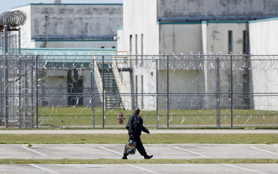 A guard crosses a prison parking lot.