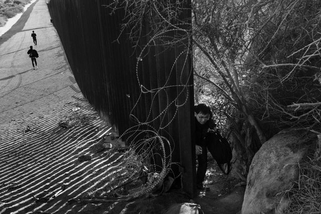 A Chinese asylum seeker kneels down to avoid barbed wire into the US near Jacumba Hot Spring, California, on Nov. 8, 2023. 