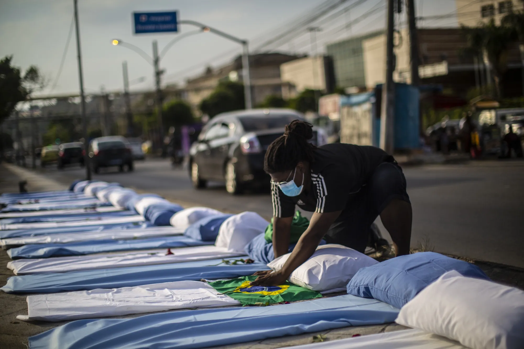 A demonstrator arranges a flag on a blanket arranged to resemble a gurney during a protest against the government's pandemic response outside of the Raul Gazzola hospital in Rio de Janeiro, Brazil, on&nbsp;March 24.