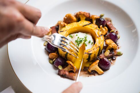 The poached egg in a thick slice of delicata squash with red wine jus and lardons.