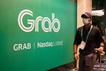 A attendee walks past a banner with a Grab logo before a bell-ringing ceremony as Grab begins trading on the Nasdaq, in Singapore, on Thursday, Dec. 2, 2021. 