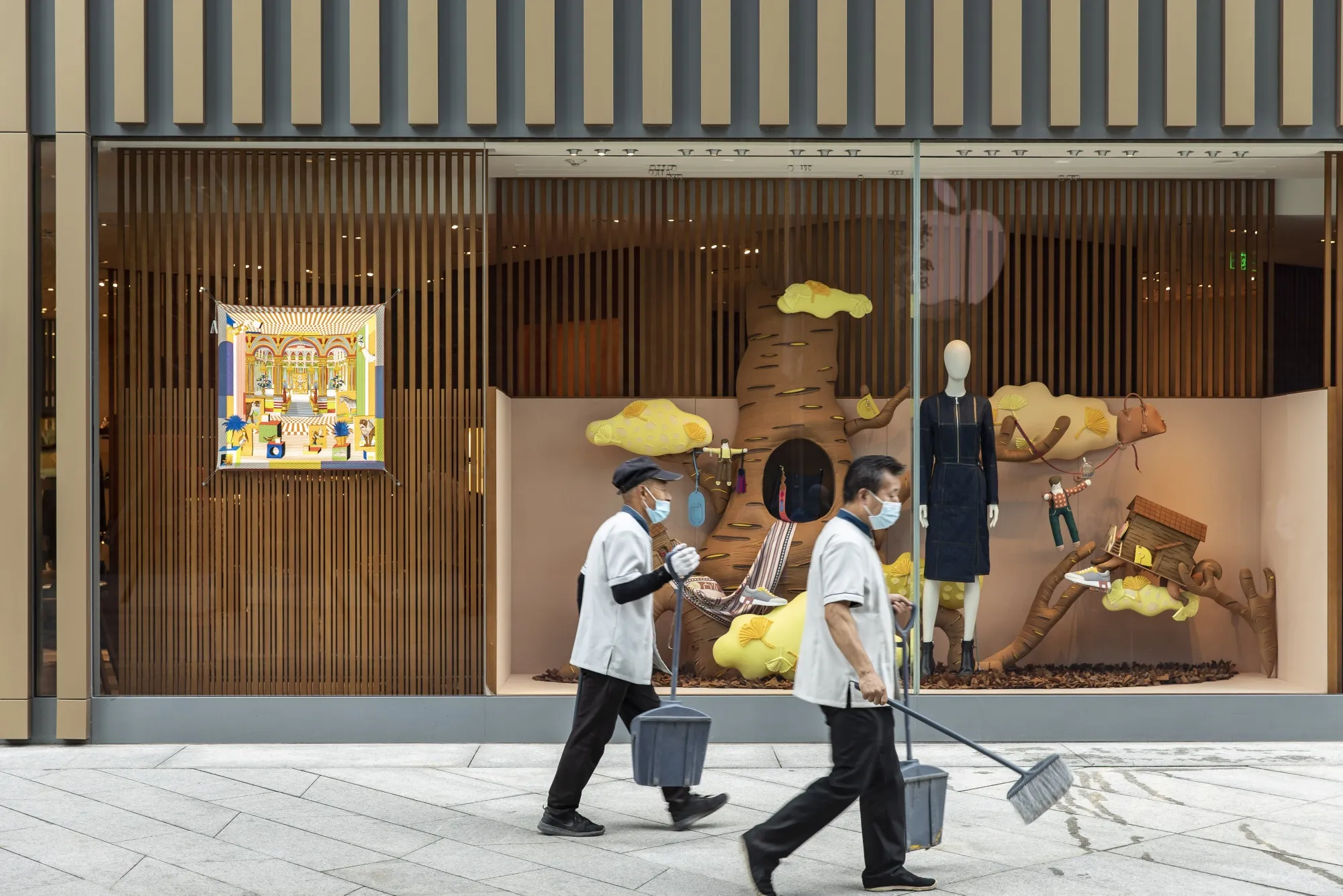 Cleaners walk past a luxury goods store at an upscale retail area in Beijing, on Aug. 25.