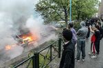 Bystanders take photos of a row of burning cars in the Stockholm suburb of Rinkeby after a riot, on May 23, 2013