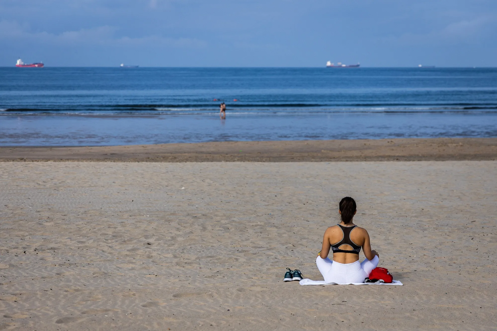 A woman meditates, presumably trying to relax after spending a small fortune on her flight,&nbsp;on the sand at Matosinhos beach on the outskirts of Porto, Portugal.&nbsp;