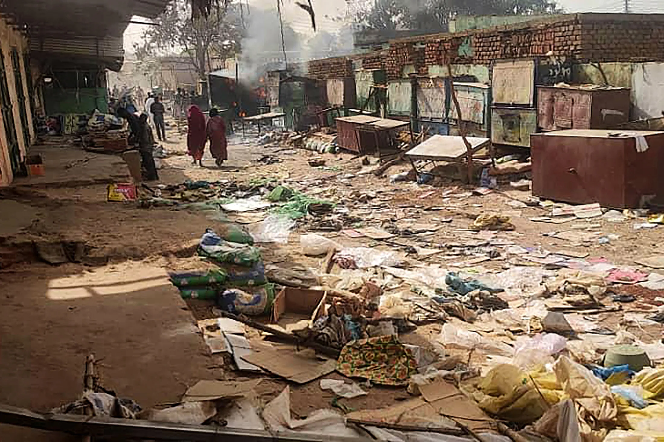 People walk among scattered objects in the market of El Geneina, in&nbsp;April 29, 2023.