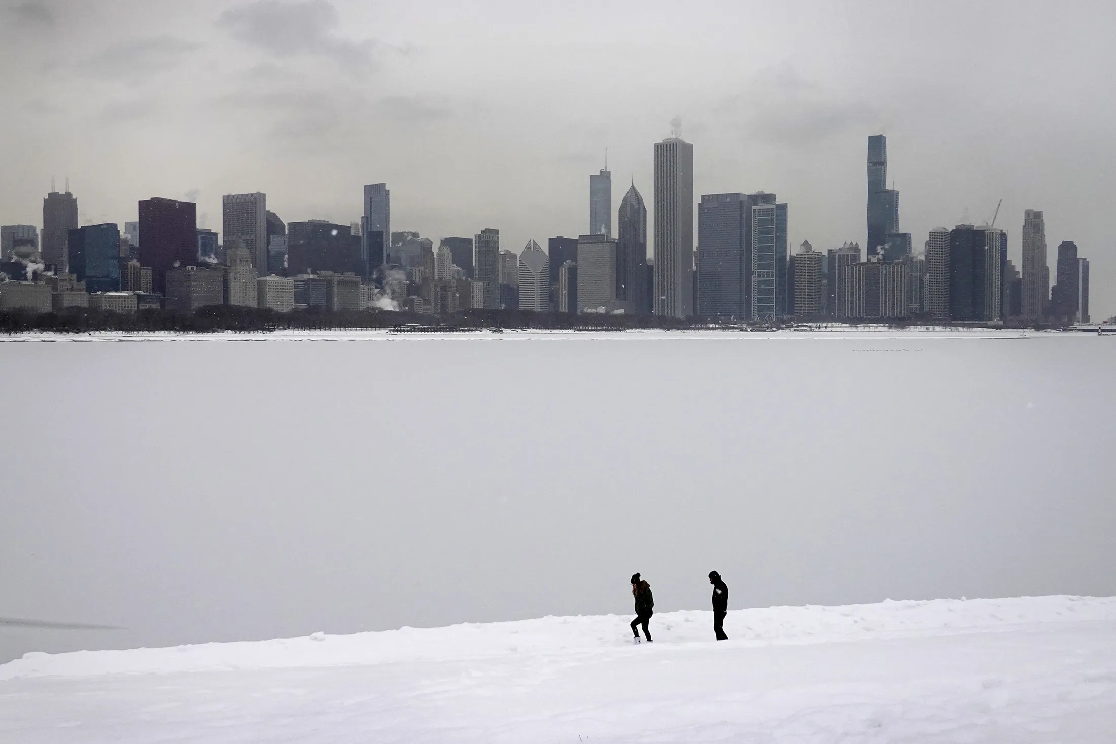 People walk along the snow-covered lakefront near downtown Chicago.