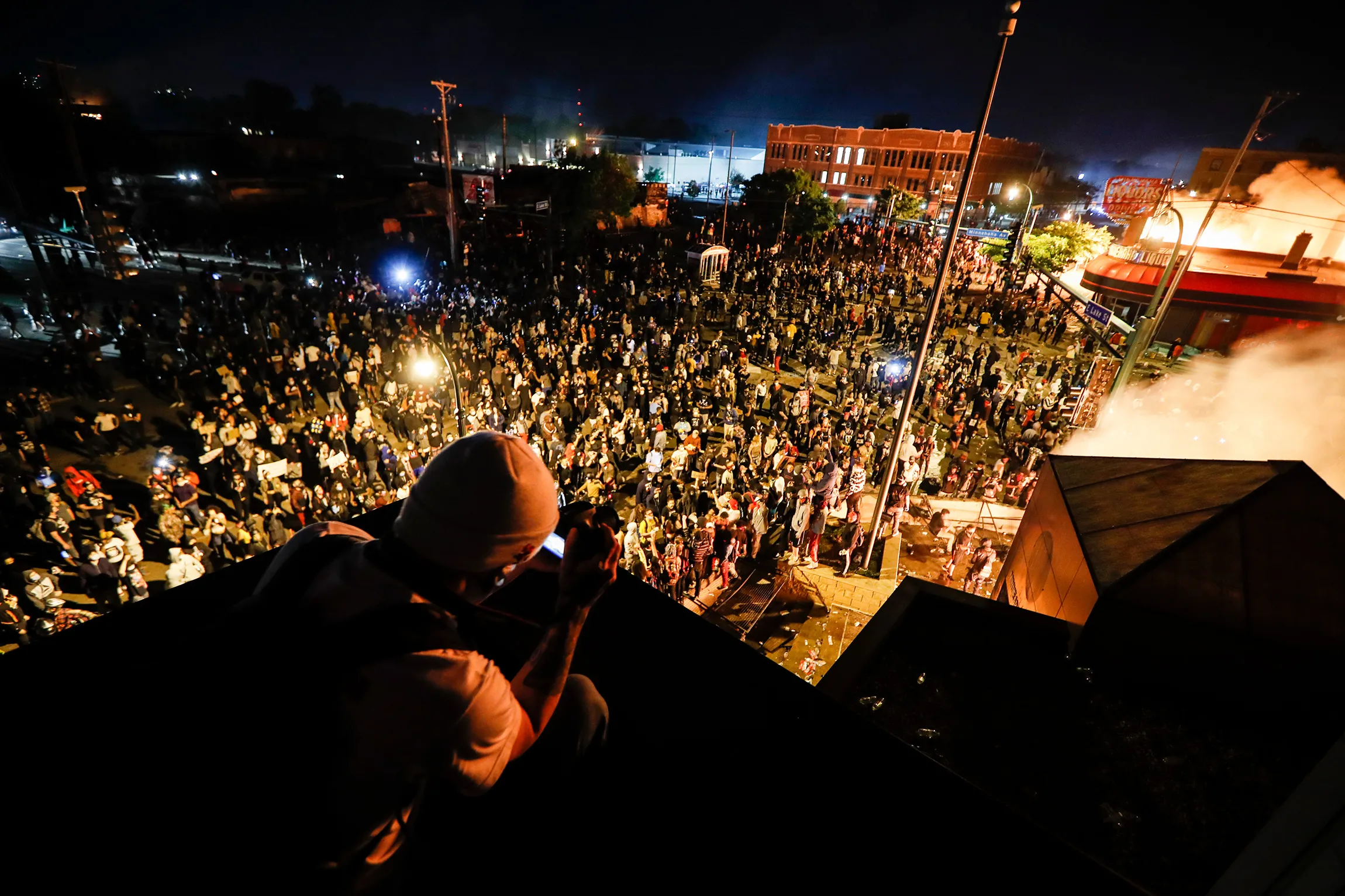 Protestors demonstrate outside the burning Minneapolis 3rd Police Precinct, on May 28.