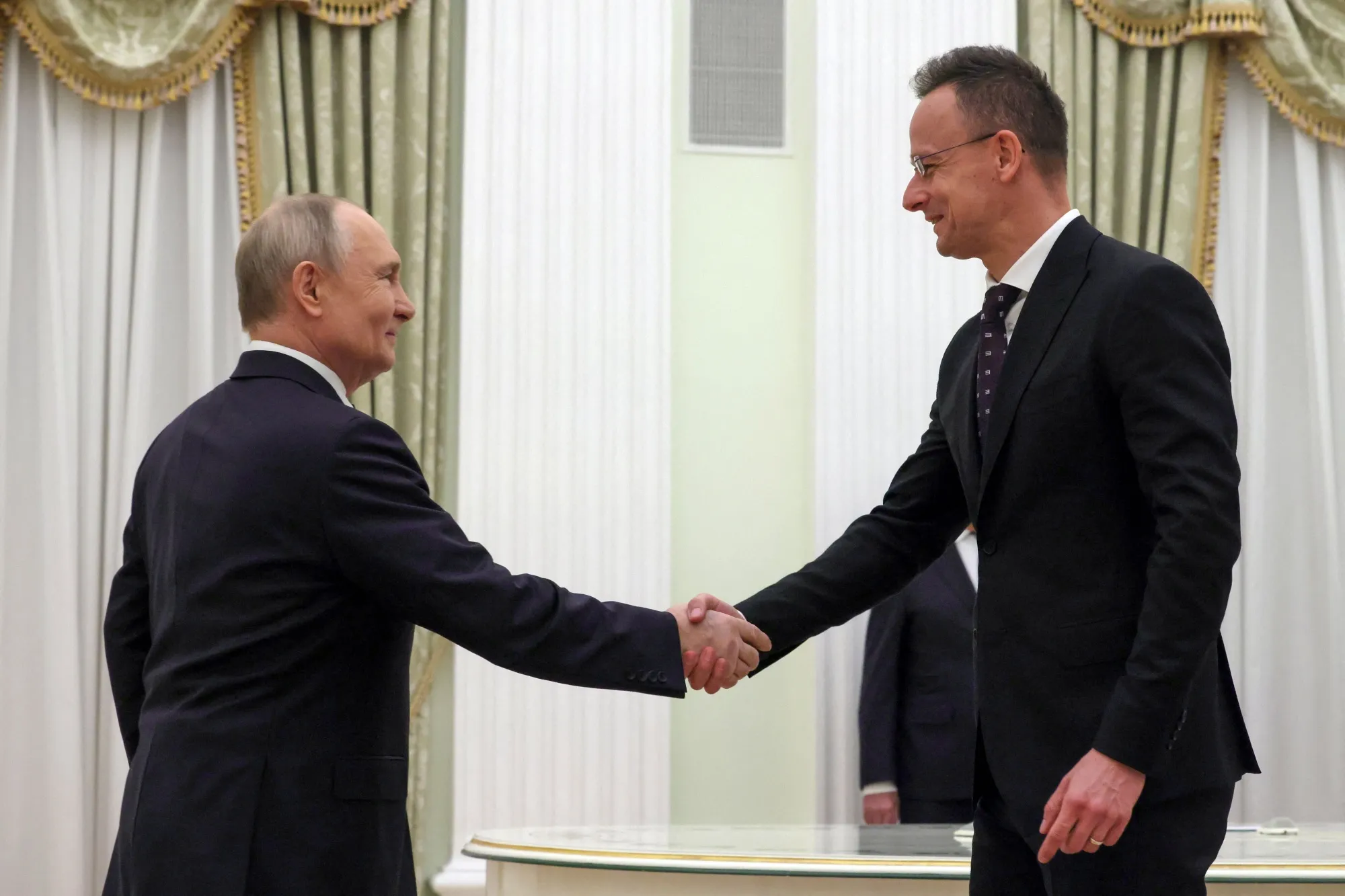 Russia's President Vladimir Putin shakes hands with Hungarian Foreign Minister Peter Szijjarto in Moscow on March 4, in this pool photo supplied by Russian state media.