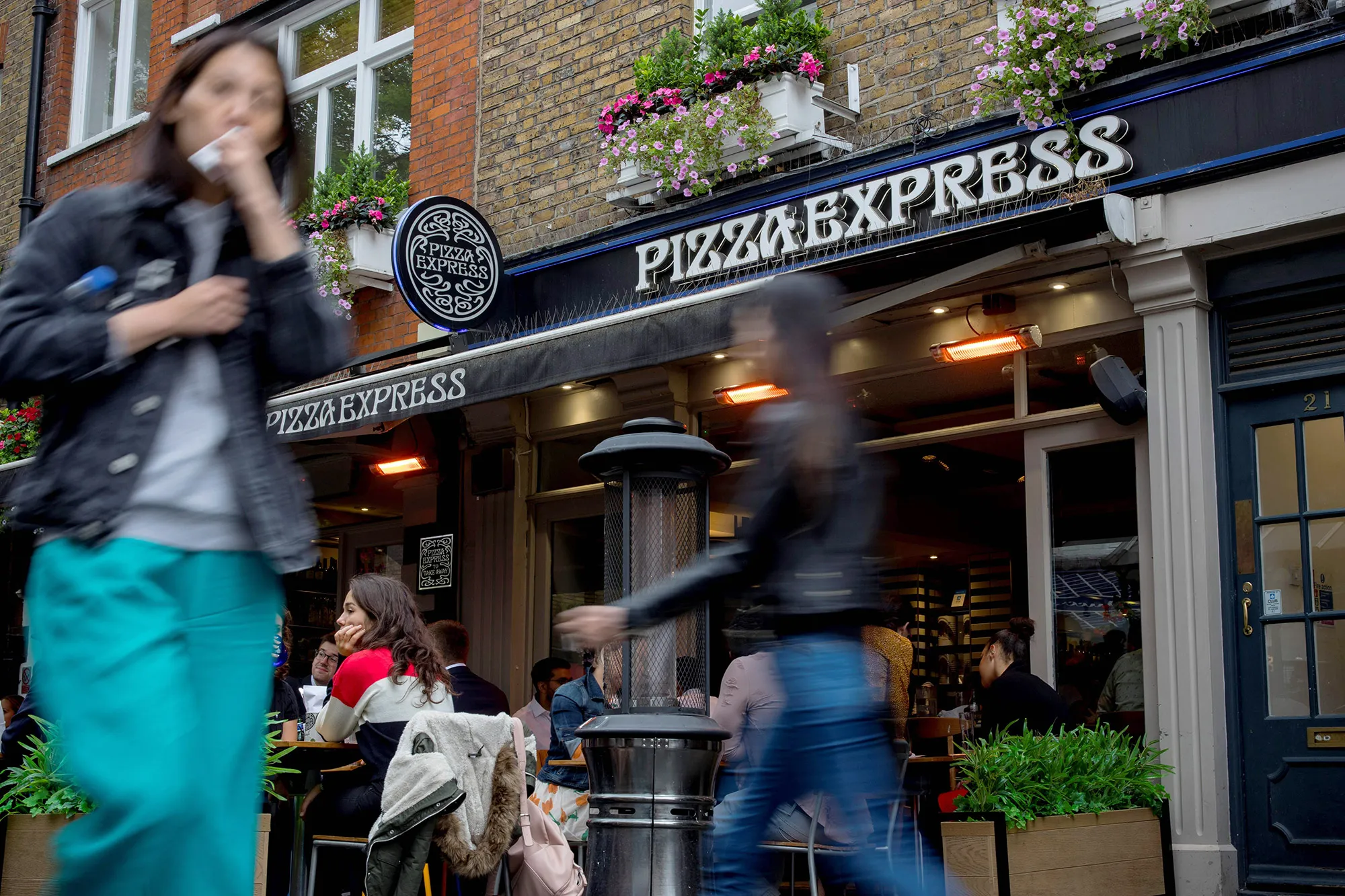 Pedestrians walk past a Pizza Express restaurant in central London.