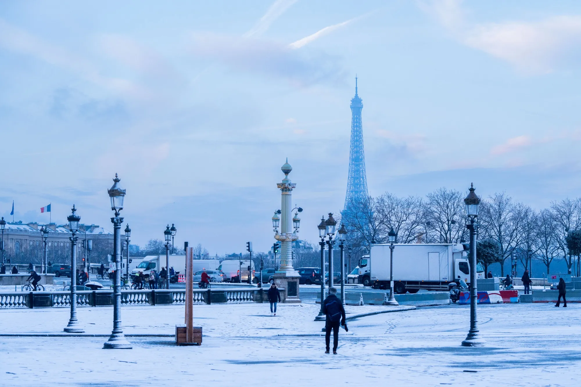 Pedestrians walk along snow-covered ground in view of the Eiffel Tower, at Place de la Concorde&nbsp;in central Paris, France.