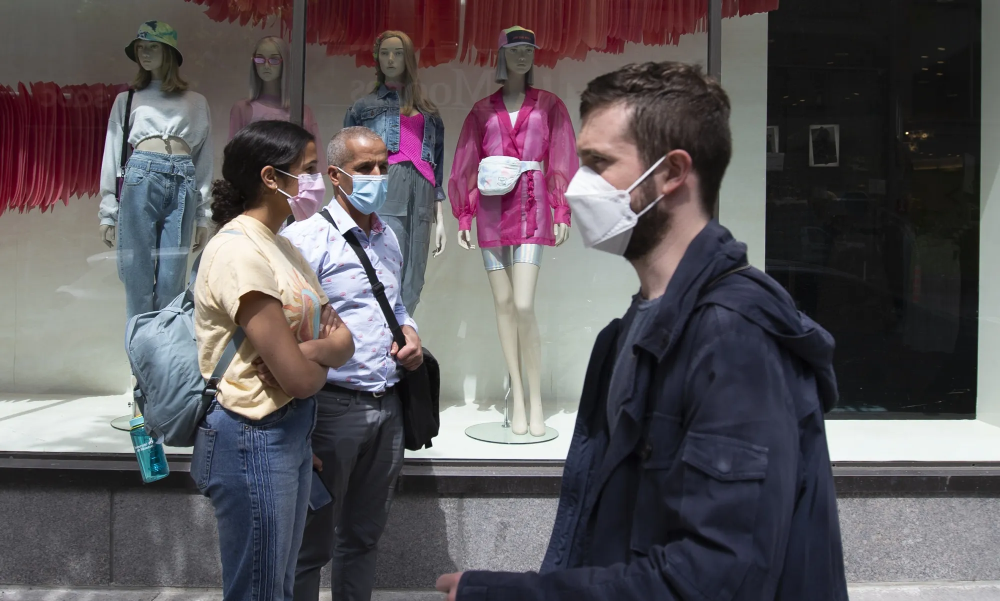 Shoppers wearing protective masks wait in line to enter at a department store in Montreal on May 25.