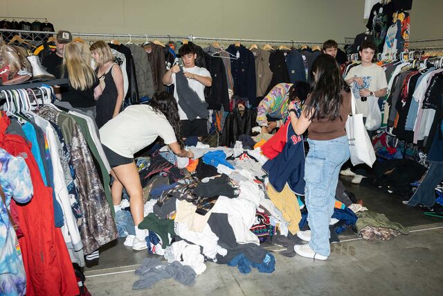 People at ThriftCon market looking at a pile of preloved clothing on the floor