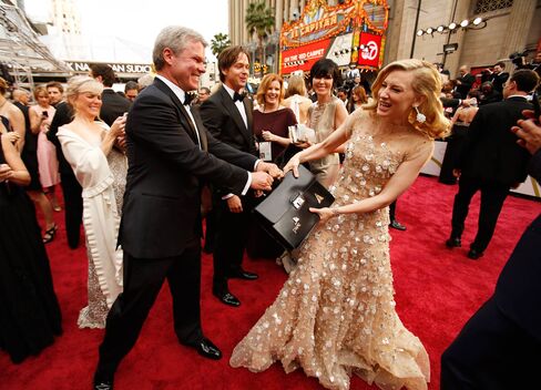 Cate Blanchett playfully tugs at the briefcase held by PwC’s Brian Cullinan as she arrives at the 86th Annual Academy Awards on March 2, 2014, at the Dolby Theatre in Hollywood, Calif.