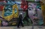 A man walks in past a grafiti&nbsp;mural on a closed building up in a street in Athens, Greece.