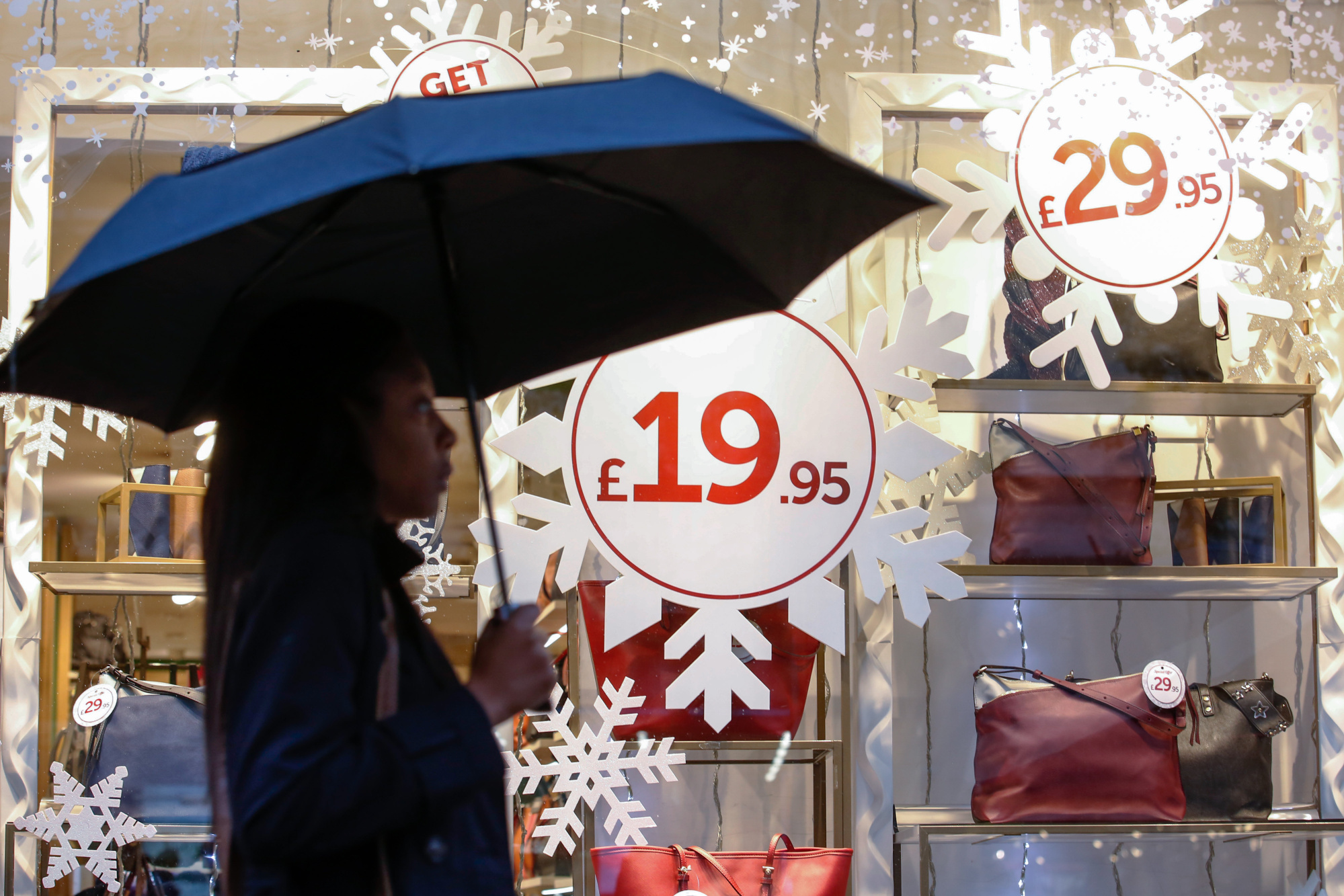 A shopper carries an umbrella past a festive window display on Oxford Street in central London, U.K., on Tuesday, Nov. 7, 2017. U.K. retail sales fell the most in seven months in October, indicating continued caution among consumers just weeks before the crucial Christmas shopping season.